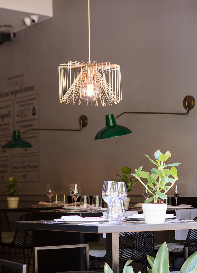 Detalle de iluminación en sala de restaurante Ornella, aplique metálico y lámpara colgante