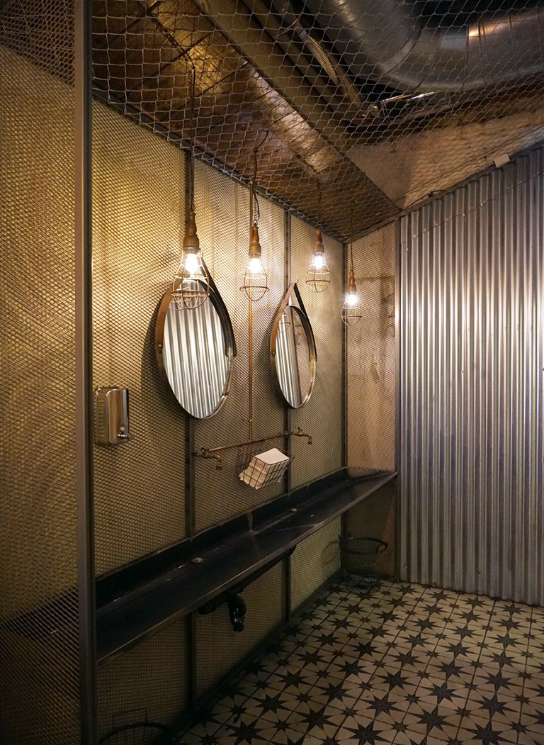 Detalle de baño, donde la iluminación juega un papel protagónico, combinado con suelo hidráulico e instalaciones vistas