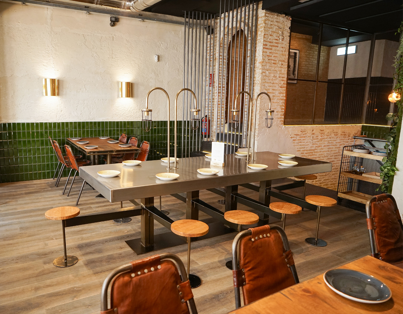Foto de comedor, paredes alicatadas a media altura, suelo en tarima, mesa metálica y bancos de madera
