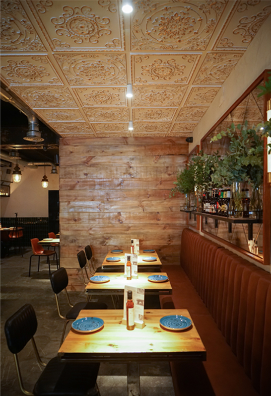 Remodelación zona de comedor con mesas bajas, molduras en techo, espejo en pared y banco corrido de terciopelo