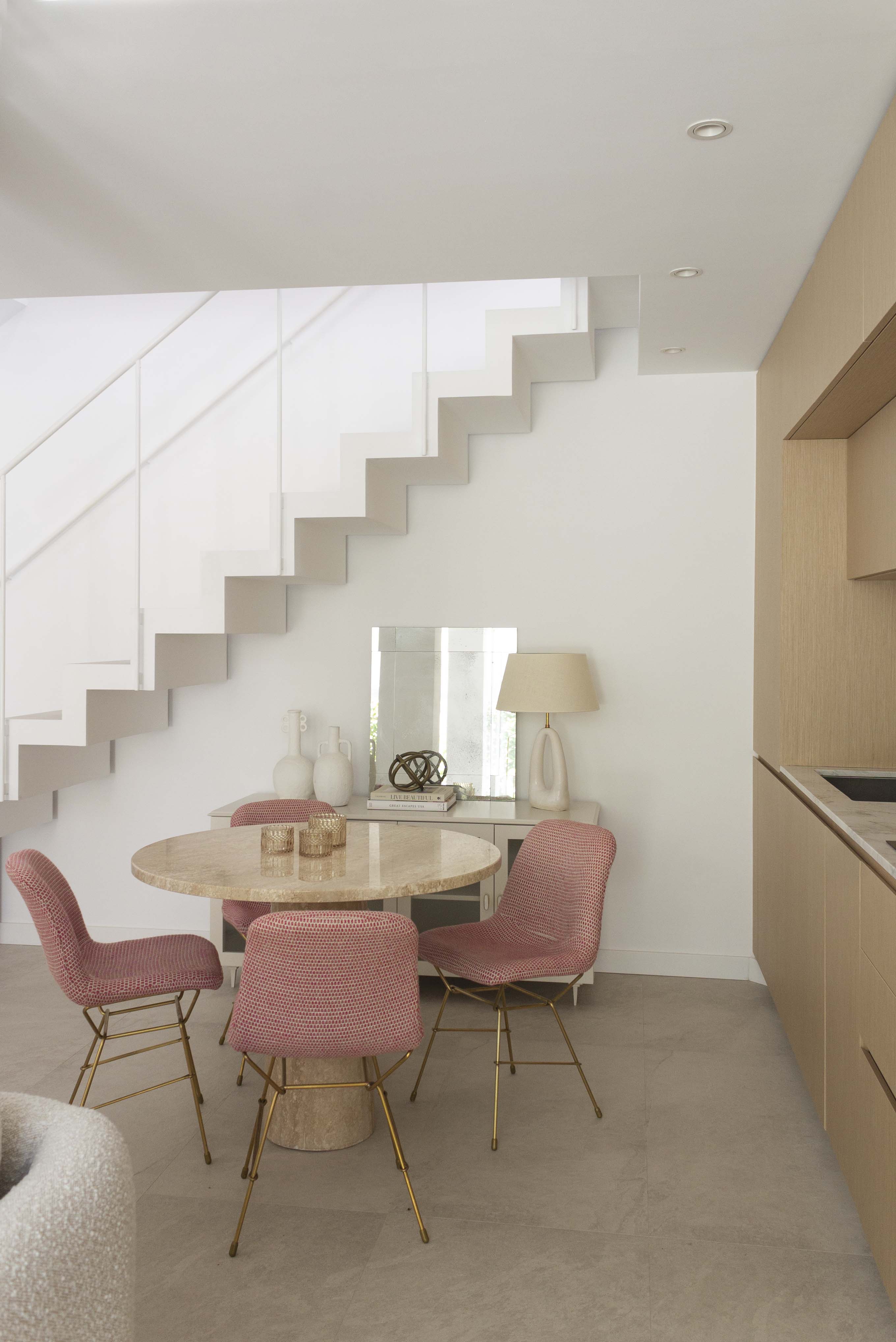 Decoracion del comedor con mesa hecha a medida de marmol travertino pulido, sillas rosadsa y mueble para vajilla hecho a medida